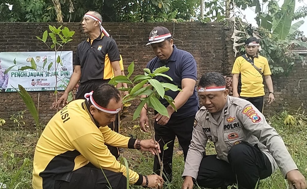 Foto : Kapolsek Cluring AKP Eko Darwaman Berkaos warna kuning menanam pohon di lingkungan RTH Lapangan Desa Benculuk. (Doc, istimewa).