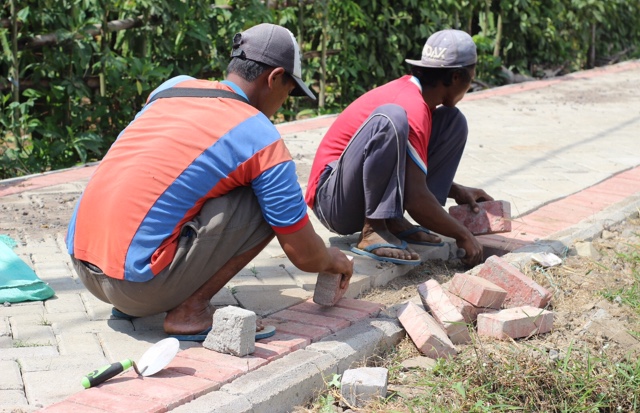 Foto : Tampak pekerja memperbaiki jalan paving yang bergelombang. (Doc, Rony).