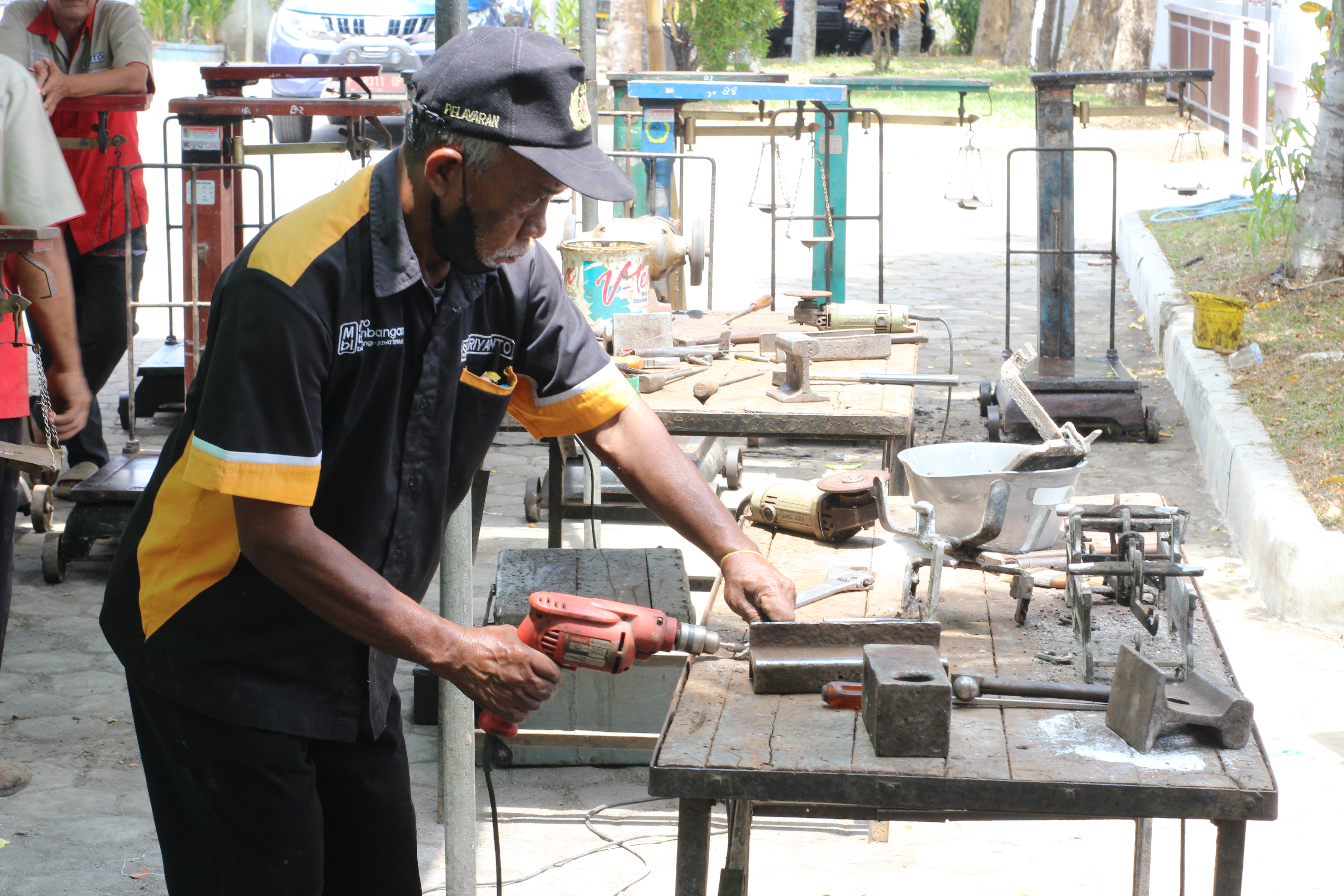 foto : Timbangan yang sudah tidak akurat dan rusak diperbaiki. tukang khusus sedang memperbaiki timbangan. (Doc. Rony).