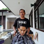 Siswandi saat memotong rambut lansia dan difabel