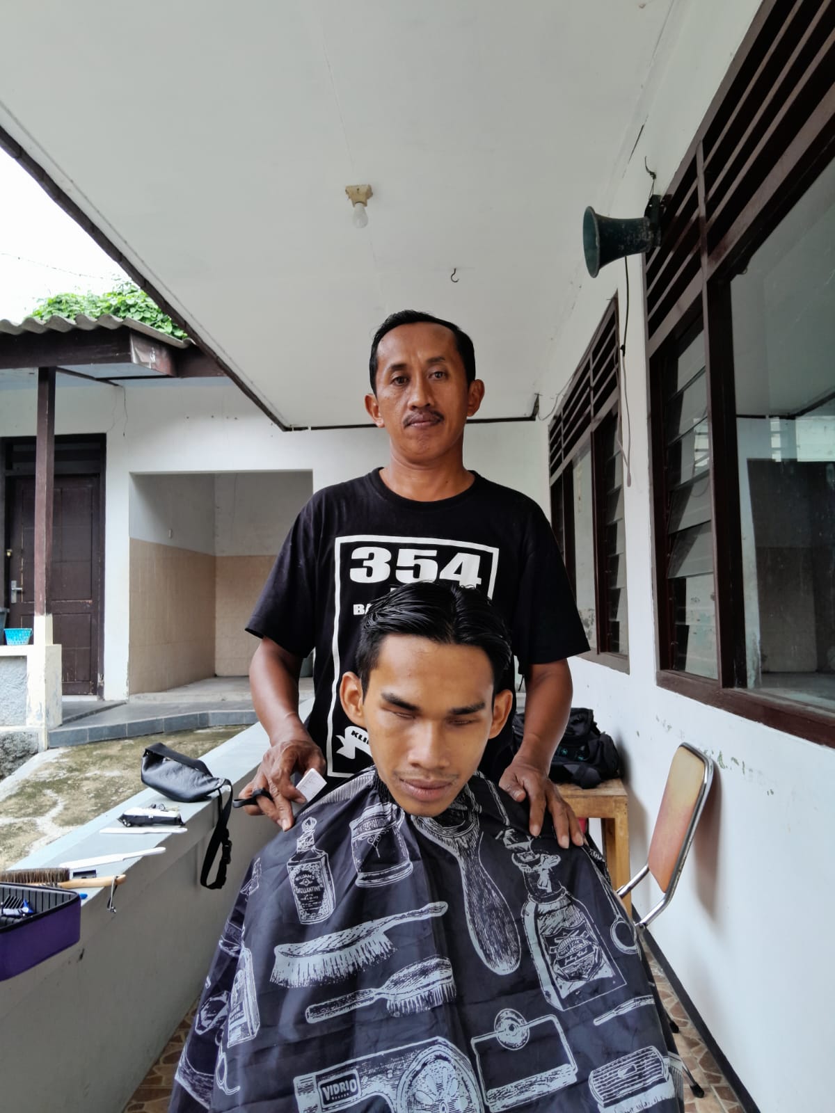 Siswandi saat memotong rambut lansia dan difabel