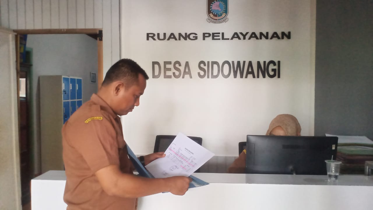 Kepala desa Sidowangi, Muansin sedang mengecek berkas